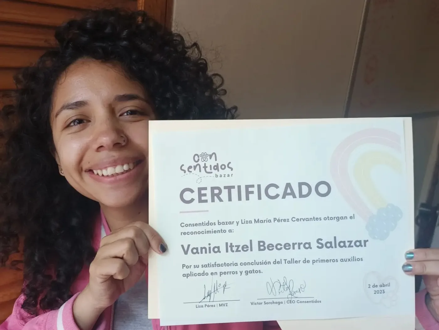 Vania Becerra sonriendo mientras sostiene su certificado de primeros auxilios para perros y gatos